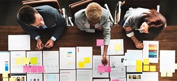 Three members of not-for-profit reviewing the uncertainties in their funding
