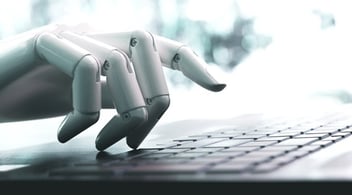 Close up of robotic hand typing on laptop