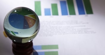A crystal ball resting on financial documents and graphs