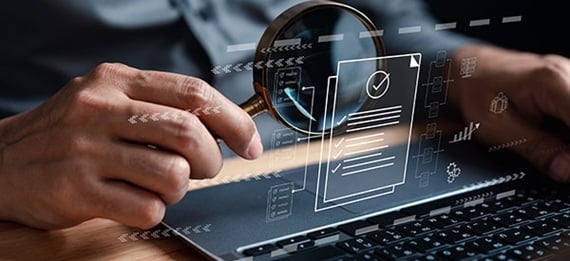 Holding magnifying glass over laptop