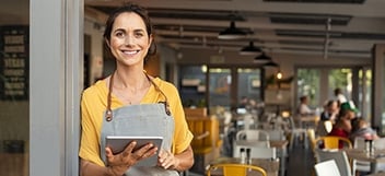 Shop owner at front of store with a tablet