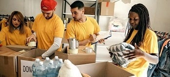 Four young professionals gathering and boxing donations