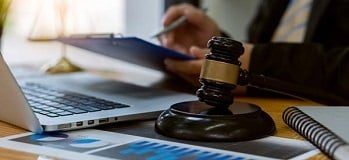 Close up of a judge's gavel next to a CPA's laptop and paperwork