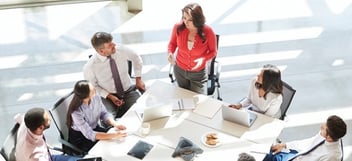 A team leader delegating assignments at a group meeting.