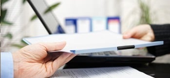 One finance team members handing off a packet to another